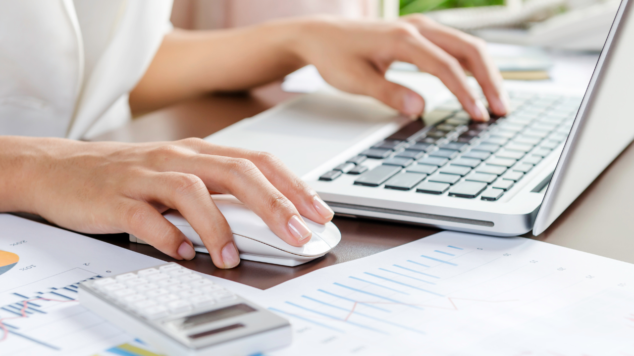 woman hands typing on keyboard and clicking mouse with papers of data